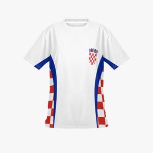 Peut inclure: T-shirt blanc avec des d&eacute;tails bleus et rouges. Le maillot pr&eacute;sente les armoiries croates sur la poitrine et des panneaux &agrave; carreaux rouges et blancs sur les c&ocirc;t&eacute;s. Les manches ont une bordure bleue.
