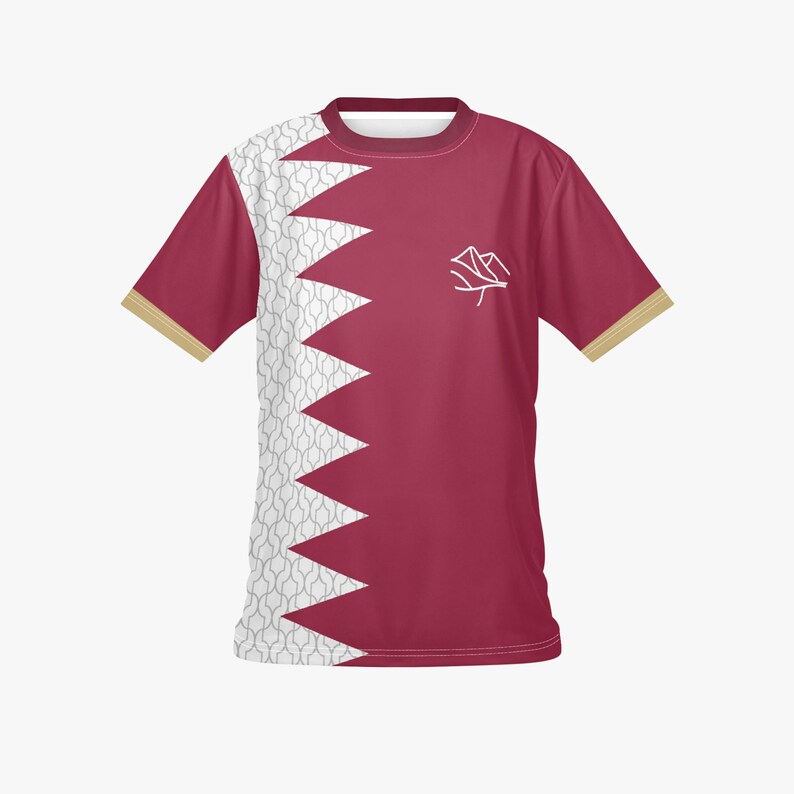 May include: Maroon t-shirt with a white and grey patterned design on the left side and a jagged edge design. The shirt has a white emblem on the right chest and gold trim on the sleeves.