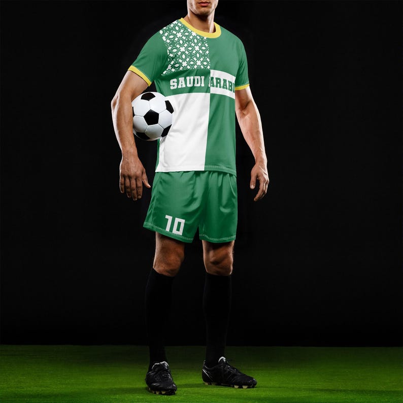 以下が含まれることがあります： 前面に「SAUDI ARAB」の文字が入った、緑と白のサッカーユニフォーム。ユニフォームには、ジャージ、背番号10のショーツ、黒い靴下が含まれています。サッカーボールが手に持たれています。