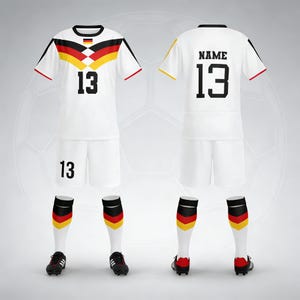 Op de afbeelding: Een compleet wit voetbaltenue met zwarte en rode accenten, met het nummer 13. Het shirt heeft een Duits vlagontwerp op de borst en schouders. Inclusief shorts, sokken en schoenen. De achterkant van het shirt heeft nummer 13 en het woord "NAME".