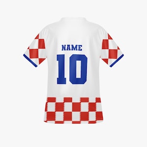 May include: White soccer jersey with blue accents and the number 10. The sleeves have red and white checkered patterns. The jersey has the word "NAME" above the number.