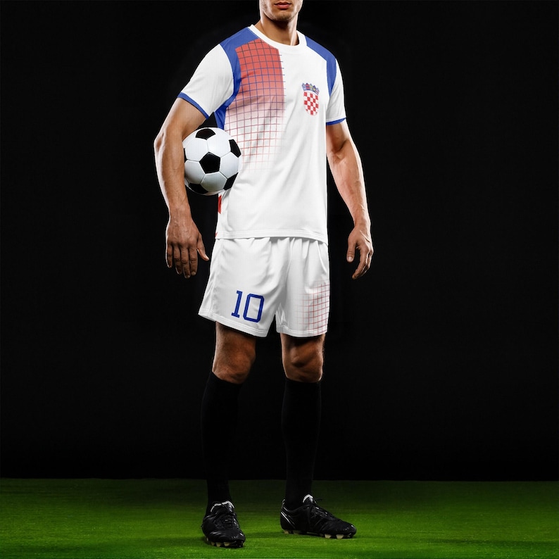 May include: A soccer uniform set in white, blue, and red, featuring a jersey with a Croatian flag emblem and shorts with the number 10. The player is holding a black and white soccer ball, standing on a green field.