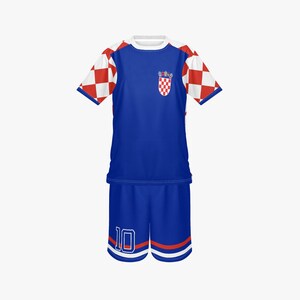 May include: A blue soccer uniform with white and red checkered sleeves. The shirt has a Croatian coat of arms on the chest and a white collar. The shorts are blue with the number 10 in white.