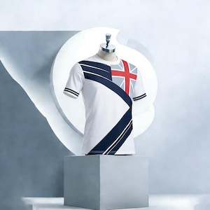 Op de afbeelding: Wit t-shirt met een marineblauw en rood ontwerp. Het shirt heeft een geometrisch patroon en een Union Jack-vlag op de rechterbovenborst. De korte mouwen hebben marineblauwe strepen.