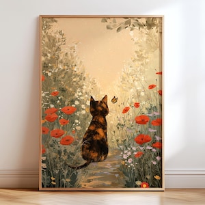 Op de afbeelding: Een ingelijste kunstdruk toont een schildpadkat die naar een vlinder op een tuinpad kijkt. De scène bevat rode klaprozen, witte wilde bloemen en groen gebladerte, wat een serene sfeer creëert. Het kunstwerk is ingelijst in een houten frame.
