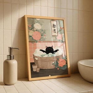 May include: Framed art print featuring a black cat relaxing in a wooden tub filled with bubbles. The artwork has a Japanese aesthetic, with floral and botanical elements in the background. The frame is light wood.