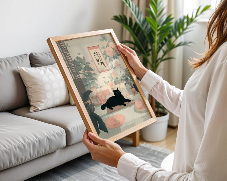 May include: A framed art print featuring a black cat lounging in a room with floral and plant decor. The artwork has a light wood frame and a soft color palette, with Japanese-inspired elements.