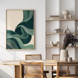 May include: A framed abstract art print featuring flowing, layered lines in shades of green and teal against a beige background. The artwork is displayed in a room with a wooden table and chairs, and a shelf with decorative items.