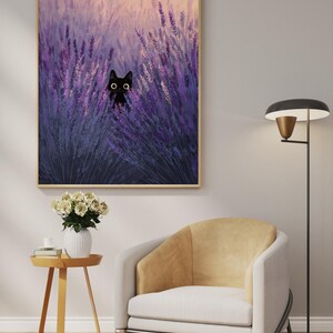 May include: A framed art print depicting a black cat amongst purple lavender. The artwork has a soft, painterly style with a warm, golden sky. The cat's eyes are wide and expressive. The print is displayed above a modern chair and side table.