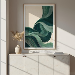 May include: Abstract art print featuring flowing, layered lines in shades of teal and green. The artwork is framed in a light wood frame and hangs above a white cabinet with a vase of dried flowers. The overall aesthetic is modern and minimalist.