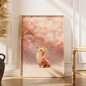 Puede incluir: Una impresi&oacute;n en acuarela enmarcada que presenta un perro corgi mirando hacia arriba bajo un cerezo en flor. La obra de arte tiene una paleta de colores pastel suaves de rosas, blancos y marrones. La impresi&oacute;n se muestra en un marco de madera clara.