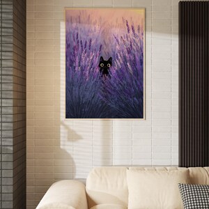 May include: A framed print depicting a black cat amongst purple lavender. The artwork has a soft, painterly style with a warm, sunset-coloured sky in the background. The frame is a light wood colour.