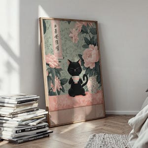 May include: A framed art print featuring a black cat holding a teacup, set against a backdrop of pink flowers and a light green background. The artwork has a vintage aesthetic, with Japanese text on the side. The print is leaning against a white wall.