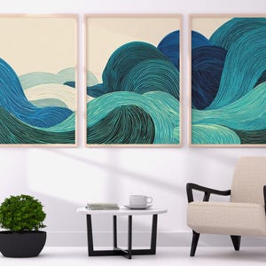 Könnte beinhalten: Drei gerahmte Kunstdrucke mit abstrakten Wellenmustern in Blau- und Türkistönen. Das Kunstwerk wird über einem modernen Stuhl, einem kleinen Tisch und einer Topfpflanze ausgestellt, wodurch eine ruhige Innenszene entsteht.