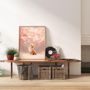 Puede incluir: Una impresi&oacute;n art&iacute;stica enmarcada que representa a un perro corgi mirando hacia arriba a un &aacute;rbol en flor rosa. La obra de arte se exhibe en una consola de madera con objetos decorativos, incluyendo un tocadiscos y plantas en macetas.