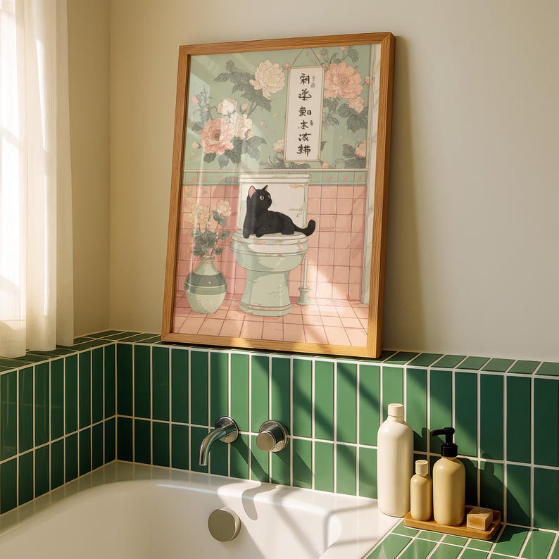 May include: A framed art print featuring a black cat lounging on a toilet. The artwork has a vintage aesthetic with floral wallpaper and a vase of flowers. The print includes Japanese text and is set in a bathroom setting.