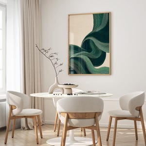 May include: An abstract art print with flowing green brushstrokes on a beige background, framed in light wood. The artwork hangs above a white marble table with three white chairs with wooden legs, creating a modern dining area.