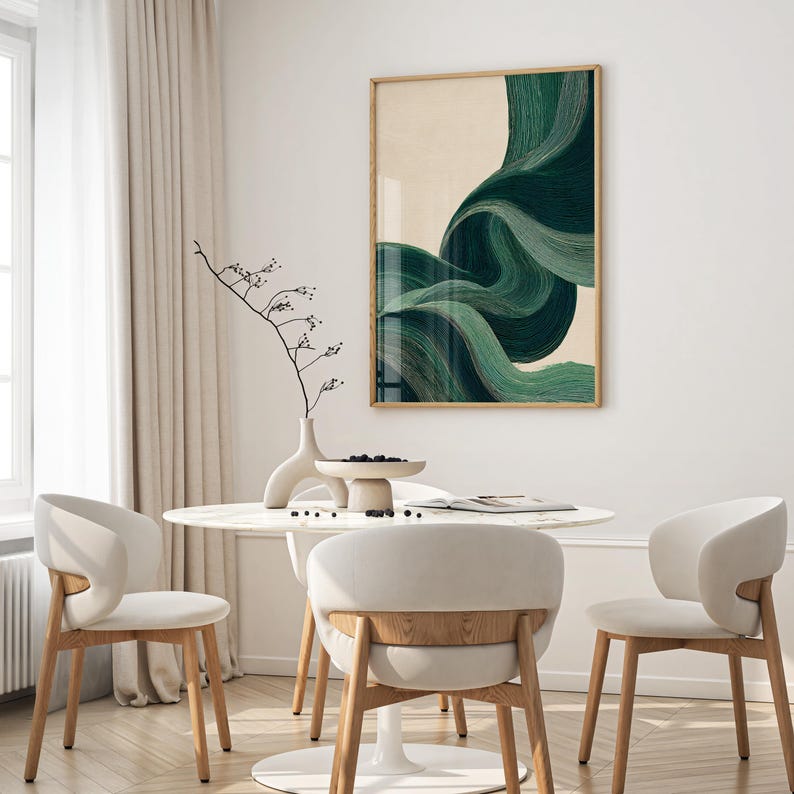 May include: An abstract art print with flowing green brushstrokes on a beige background, framed in light wood. The artwork hangs above a white marble table with three white chairs with wooden legs, creating a modern dining area.