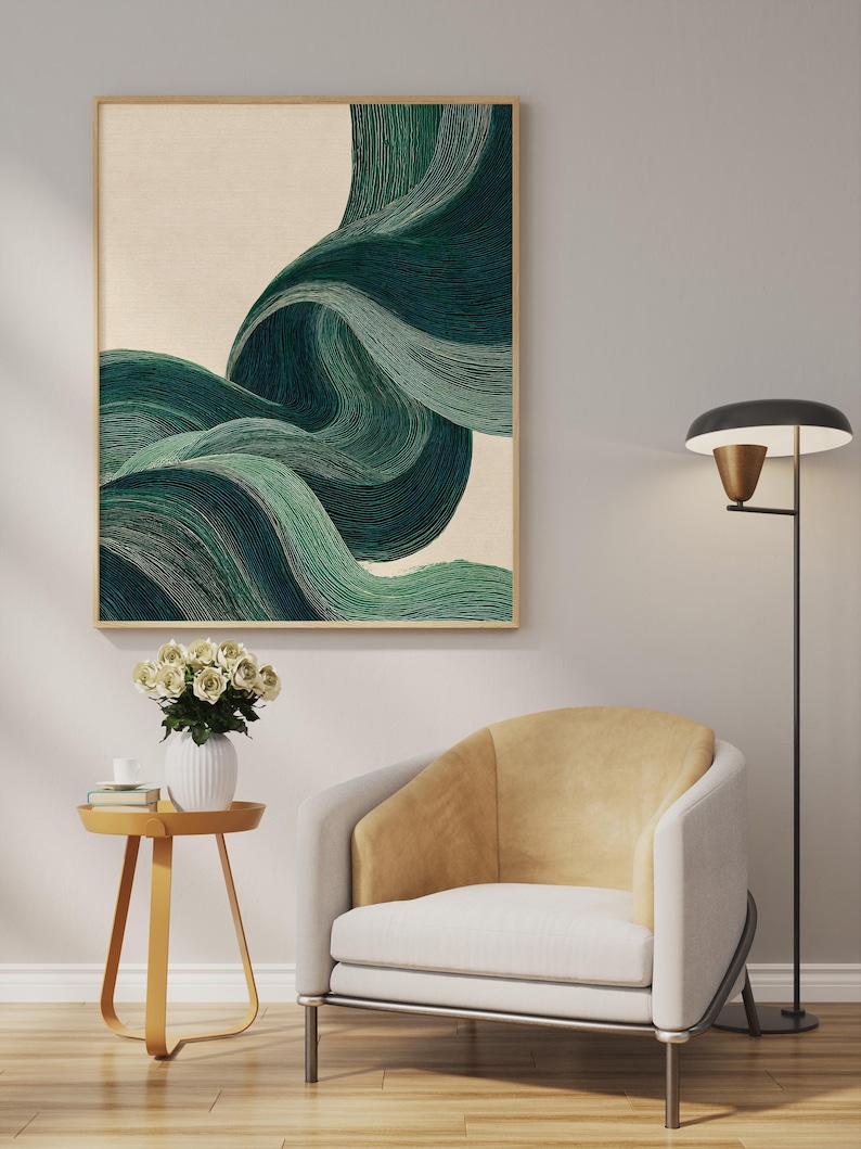 May include: Abstract art print featuring flowing, layered green and teal brushstrokes against a cream background, framed in a light wood. The artwork hangs above a modern armchair with a yellow back and a small side table with a vase of white flowers.