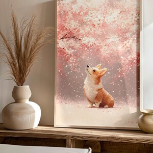 Puede incluir: Una impresi&oacute;n art&iacute;stica enmarcada que presenta un perro corgi mirando hacia arriba bajo un cerezo en flor. La obra de arte tiene un estilo suave y pict&oacute;rico con tonos de rosa, blanco y marr&oacute;n. La impresi&oacute;n se exhibe en una estanter&iacute;a de madera con elementos decorativos.
