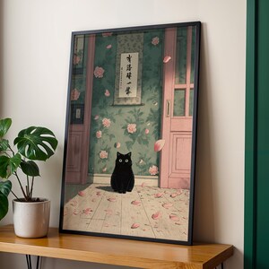 May include: Framed art print featuring a black cat with large eyes, sitting on a wooden floor scattered with pink petals. The background shows a room with floral wallpaper, a pink door, and a scroll with Japanese text.