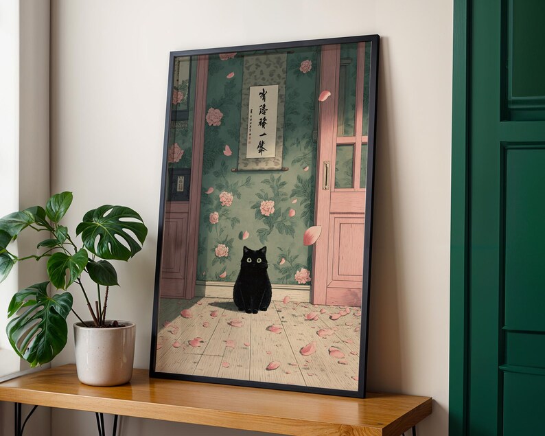 May include: Framed art print featuring a black cat with large eyes, sitting on a wooden floor scattered with pink petals. The background shows a room with floral wallpaper, a pink door, and a scroll with Japanese text.