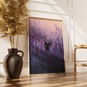 May include: A framed art print depicting a black cat in a lavender field. The artwork is in a gold frame, set on a wooden floor. A decorative vase with dried plants is to the left. The print is approximately 60 cm high.