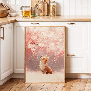 Puede incluir: Una impresi&oacute;n enmarcada en acuarela que presenta un perro corgi mirando hacia arriba a un cerezo en flor. La obra de arte tiene una paleta de colores pastel suaves de rosa, blanco y marr&oacute;n. El marco es de color marr&oacute;n claro.