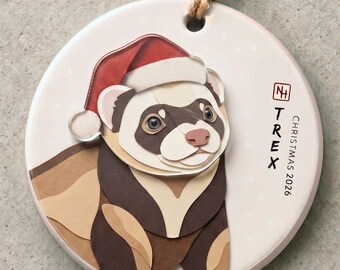 May include: A round ceramic ornament featuring a ferret wearing a red and white Santa hat. The ornament includes a brown hanging cord and the text "NH TREX CHRISTMAS 2026" printed in black on the right side against a light cream background.