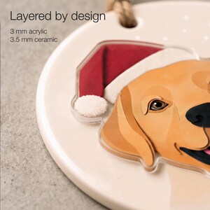Close-up of the golden Labrador portrait showing printed paper-cut shading, a 3.5 mm matte ceramic base and a 3 mm clear acrylic overlay on the head and Santa hat.