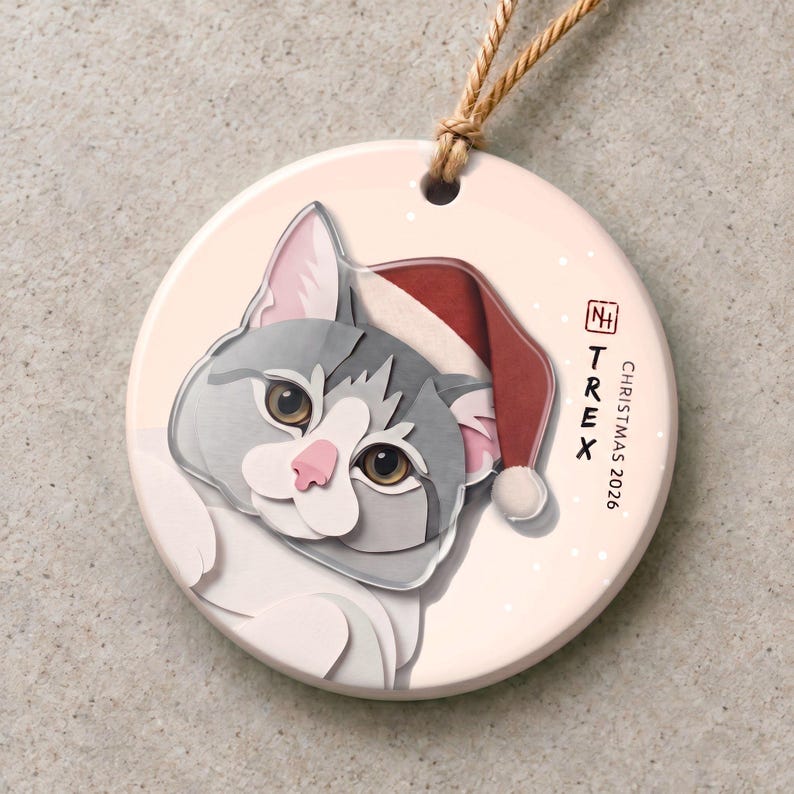 Personalized Christmas ornament featuring a grey-and-white cat named TREX, with a matte ceramic base and a clear acrylic portrait layer.