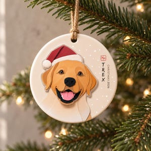 Personalized golden Labrador Christmas ornament hanging on an evergreen branch in a calm, warmly lit holiday setting.