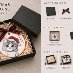 May include: A Christmas gift box set containing a round ceramic ornament with a gray and white cat illustration wearing a red Santa hat, a black and red plaid ribbon, and ivory shredded paper filler, with assembly instructions.