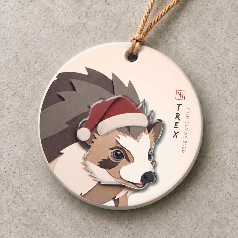 Personalized hedgehog Christmas ornament with a 3.5 mm matte ceramic base and a separate 3 mm clear acrylic portrait-and-Santa-hat layer.