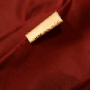 May include: A close-up of a brown fabric label with the text "LINING 100% ACETATE" printed in black.