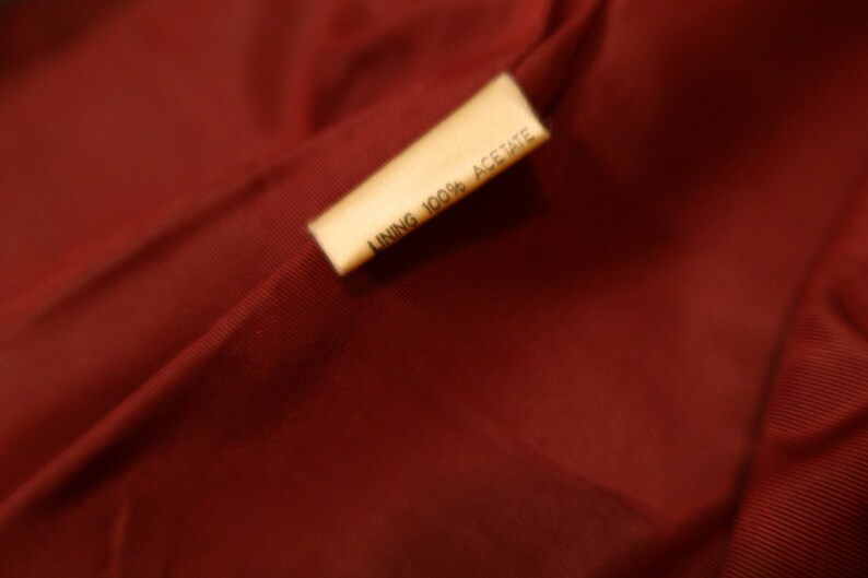 May include: A close-up of a brown fabric label with the text "LINING 100% ACETATE" printed in black.