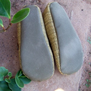 May include: A pair of brown and beige slippers with a textured fabric upper and a gray suede sole.