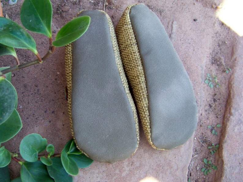 May include: A pair of brown and beige slippers with a textured fabric upper and a gray suede sole.