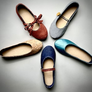 May include: Five pairs of women's flats in different colors and materials. The flats are arranged in a star shape on a white background. The flats include a pair of brown suede flats with a bow, a pair of light blue canvas flats, a pair of cork flats, a pair of light blue suede flats, and a pair of dark blue leather flats.