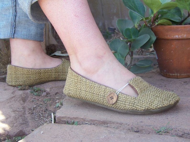 May include: A pair of woven, beige flats with a button detail on the strap. The shoes have a closed toe and a low heel.