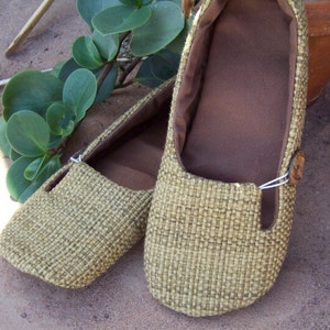 May include: A pair of brown woven flat shoes with a brown fabric lining. The shoes have a simple design and are made of a natural material.