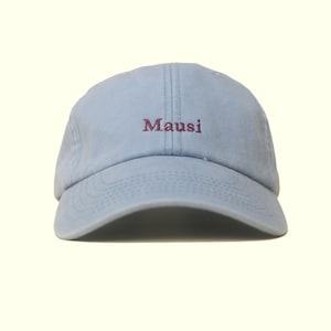 Könnte beinhalten: Hellblaue Baseballkappe mit dem Wort "Mausi" in dunklerem Lila gestickt. Die Kappe hat einen gebogenen Schirm und ein klassisches Sechs-Panel-Design, geeignet für den lässigen Gebrauch.
