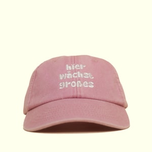 Peut inclure: Casquette de baseball rose avec le texte allemand "hier wächst großes" brodé en blanc. La casquette a une visière incurvée et une conception classique à six panneaux, parfaite pour un usage quotidien.