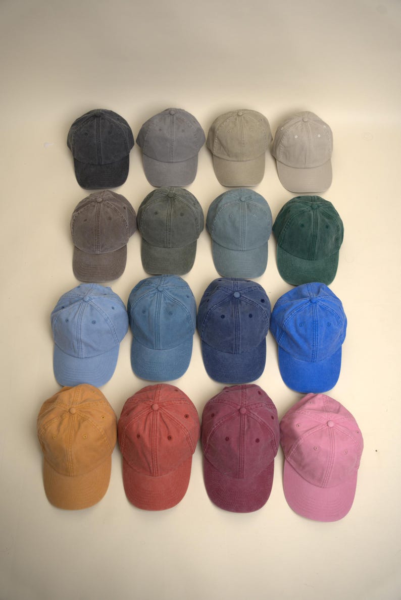 Op de afbeelding: Een verzameling van vijftien baseballpetten in verschillende kleuren, waaronder marineblauw, grijs, groen, blauw, oranje, rood en roze. De petten zijn gerangschikt in rijen en kolommen, met een scala aan tinten en stijlen. De petten zijn gemaakt van een zacht materiaal.