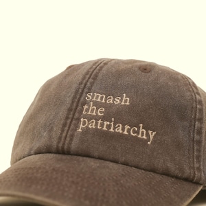 Op de afbeelding: Bruine baseballcap met de geborduurde tekst "smash the patriarchy" in lichtbruin. De cap heeft een gebogen klep en een klassiek zes-panelen ontwerp, geschikt voor dagelijks gebruik.