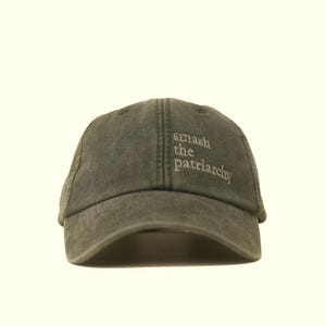 Op de afbeelding: Olijfgroene baseballcap met de geborduurde tekst "smash the patriarchy" in het wit. De cap heeft een gebogen klep en een klassiek zes-panelen ontwerp. Een casual accessoire.