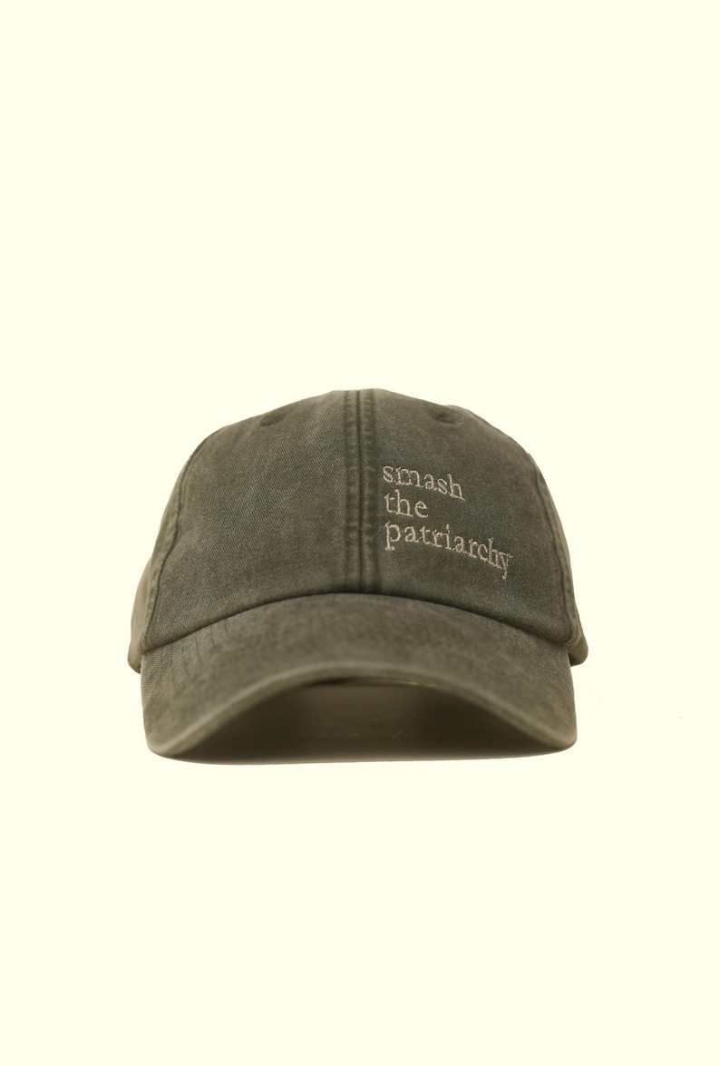 Op de afbeelding: Olijfgroene baseballcap met de geborduurde tekst "smash the patriarchy" in het wit. De cap heeft een gebogen klep en een klassiek zes-panelen ontwerp. Een casual accessoire.