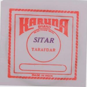 May include: A white label with red and purple text. The label reads "KARUNA BRAND" at the top, with "SITAR" in the center, and "TARAFDAR" below. The label is framed with a red border and the words "MADE IN INDIA" are at the bottom.