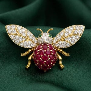 Puede incluir: Broche de abeja dorada con detalles de rubíes y diamantes. El cuerpo de la abeja está formado por rubíes rojos agrupados, mientras que las alas están incrustadas con diamantes. Los ojos son pequeñas gemas verdes. Fondo verde oscuro.