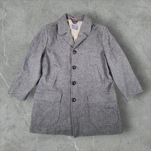 May include: A gray tweed coat featuring a notched collar, four dark brown buttons down the center front, two large flap pockets at the hips, and two slanted welt pockets at the chest. The interior features a light beige lining and a Pendleton label.